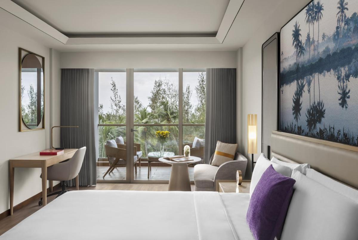 a bedroom with a bed and a living room at Vivanta Goa, Miramar in Panaji a bedroom with a bed and a living room at Vivanta Goa, Miramar in Panaji
