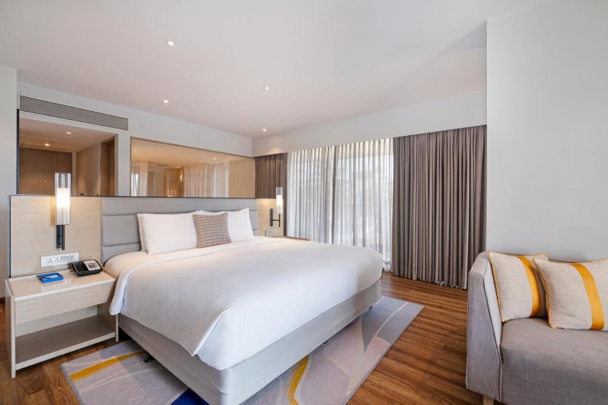 a bedroom with a large white bed and a couch at Vivanta Goa, Miramar in Panaji a bedroom with a large white bed and a couch at Vivanta Goa, Miramar in Panaji