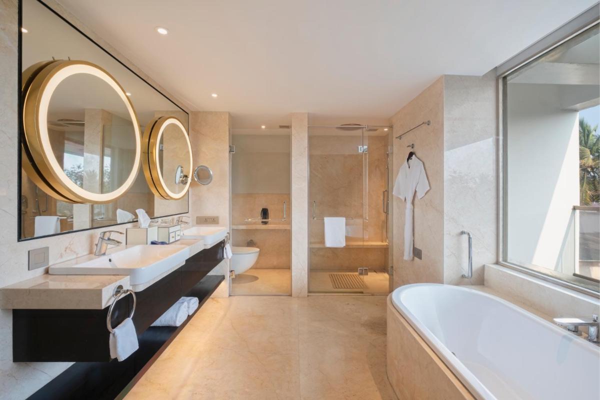a bathroom with two sinks and a tub and a shower at Vivanta Goa, Miramar in Panaji a bathroom with two sinks and a tub and a shower at Vivanta Goa, Miramar in Panaji