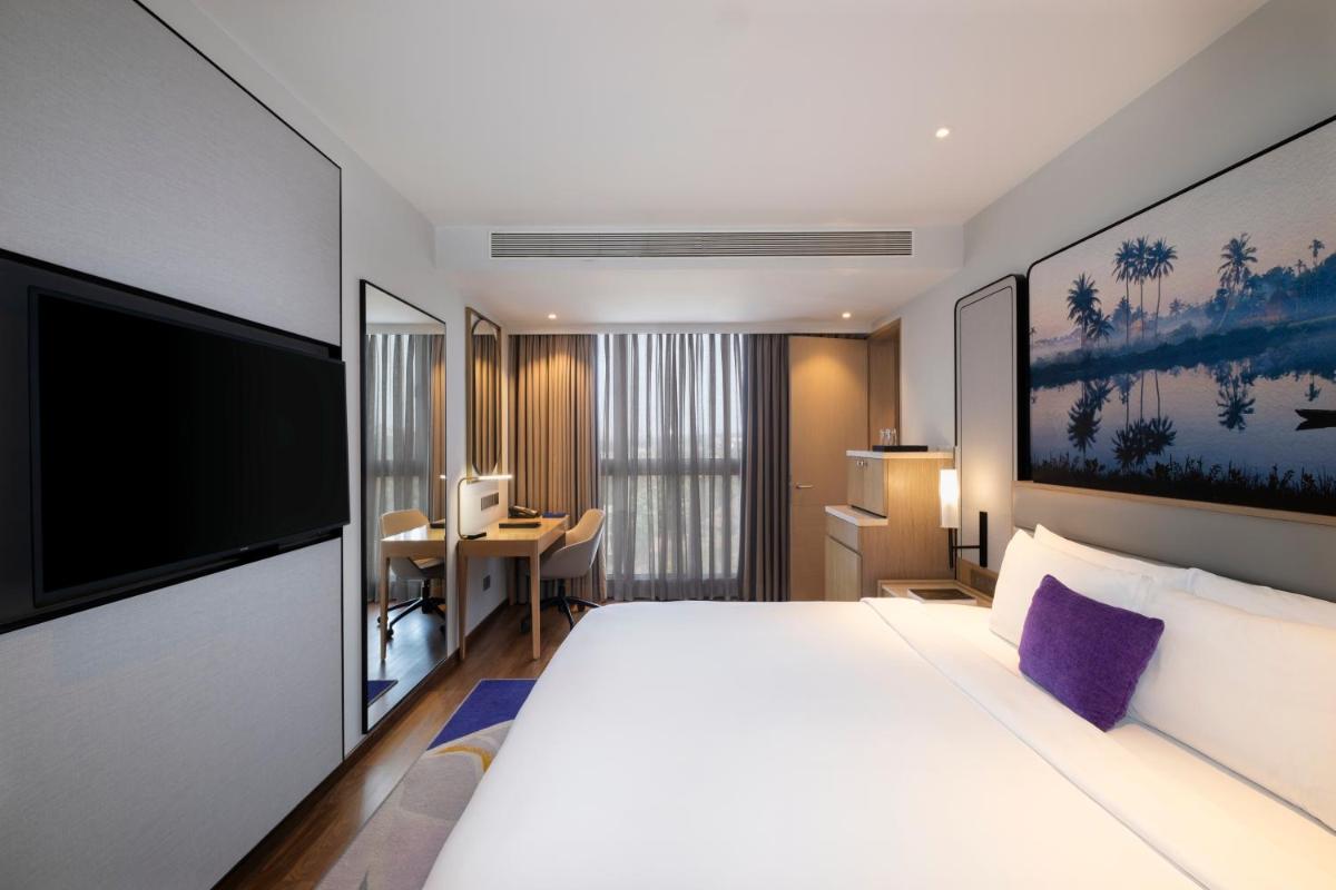 a hotel room with a large bed and a flat screen tv at Vivanta Goa, Miramar in Panaji a hotel room with a large bed and a flat screen tv at Vivanta Goa, Miramar in Panaji