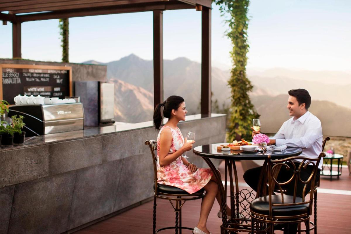 a man and woman sitting at a table on a patio at JW Marriott Mussoorie Walnut Grove Resort & Spa in Mussoorie
