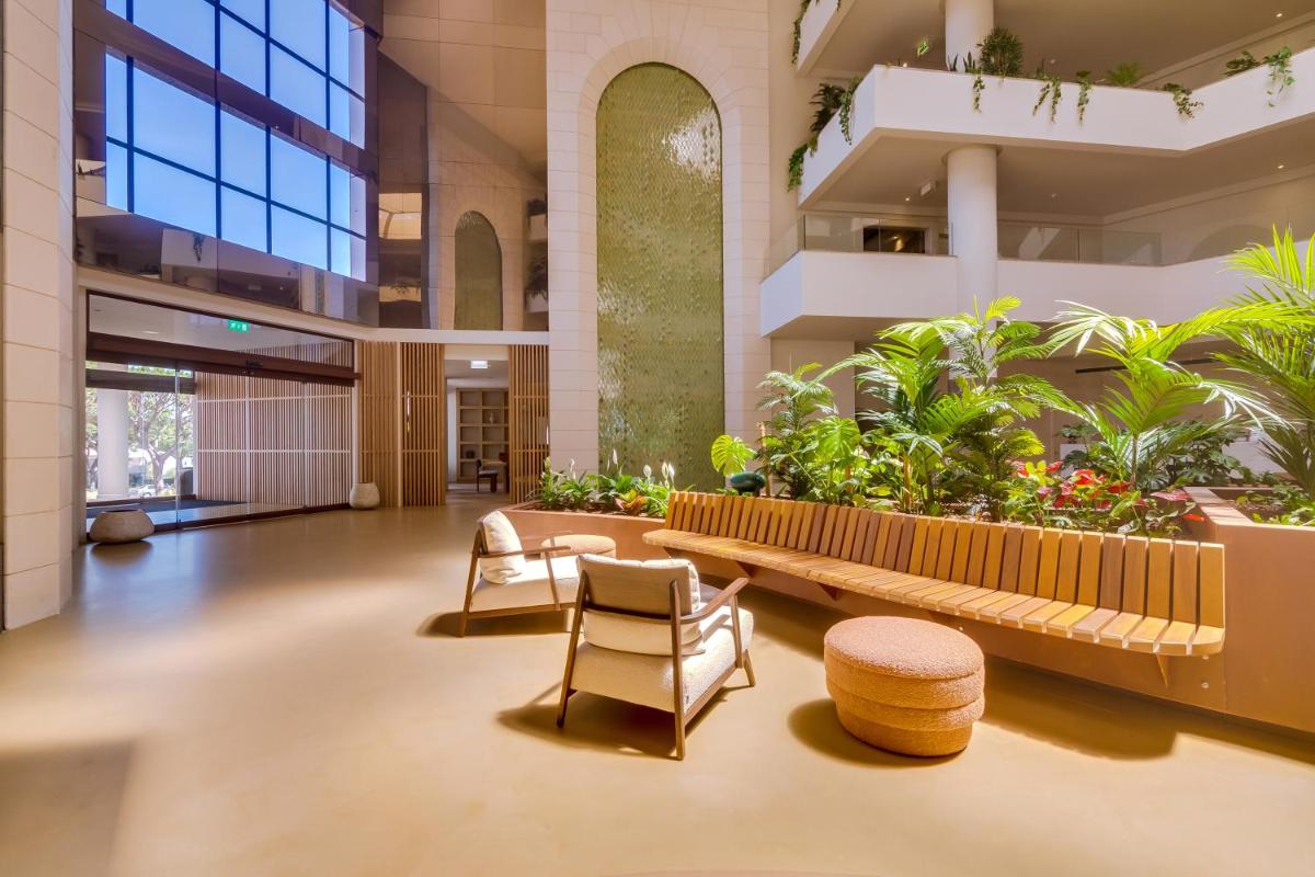 um saguão com cadeiras e plantas em um prédio em Falésia Hotel - Adults Only em Albufeira