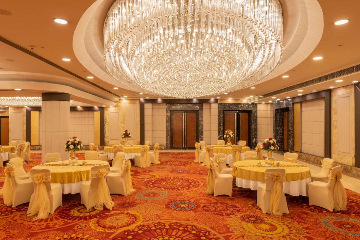 a banquet hall with tables and a large chandelier at Radisson Blu Kaushambi Delhi NCR in Ghaziabad