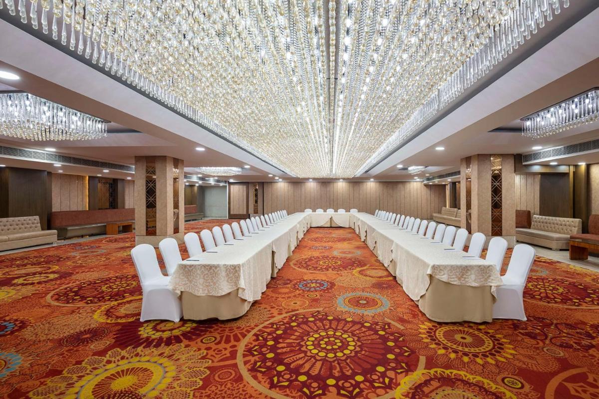 a banquet hall with white chairs and a large ceiling at Radisson Blu Kaushambi Delhi NCR in Ghaziabad