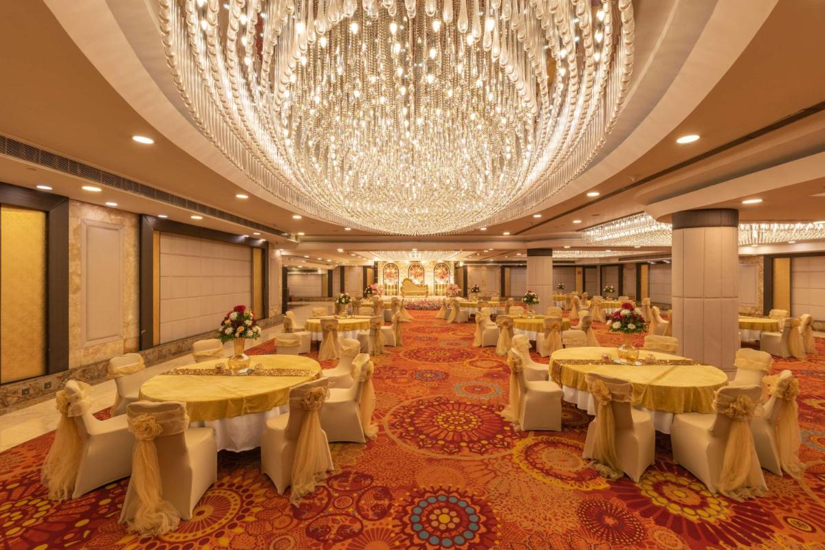 a banquet hall with tables and chairs and a large chandelier at Radisson Blu Kaushambi Delhi NCR in Ghaziabad