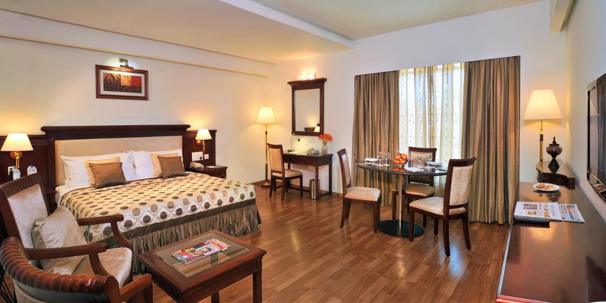 a hotel room with a bed and a table and chairs at Fortune JP Palace, Mysore - Member ITC Hotels' Group in Mysore