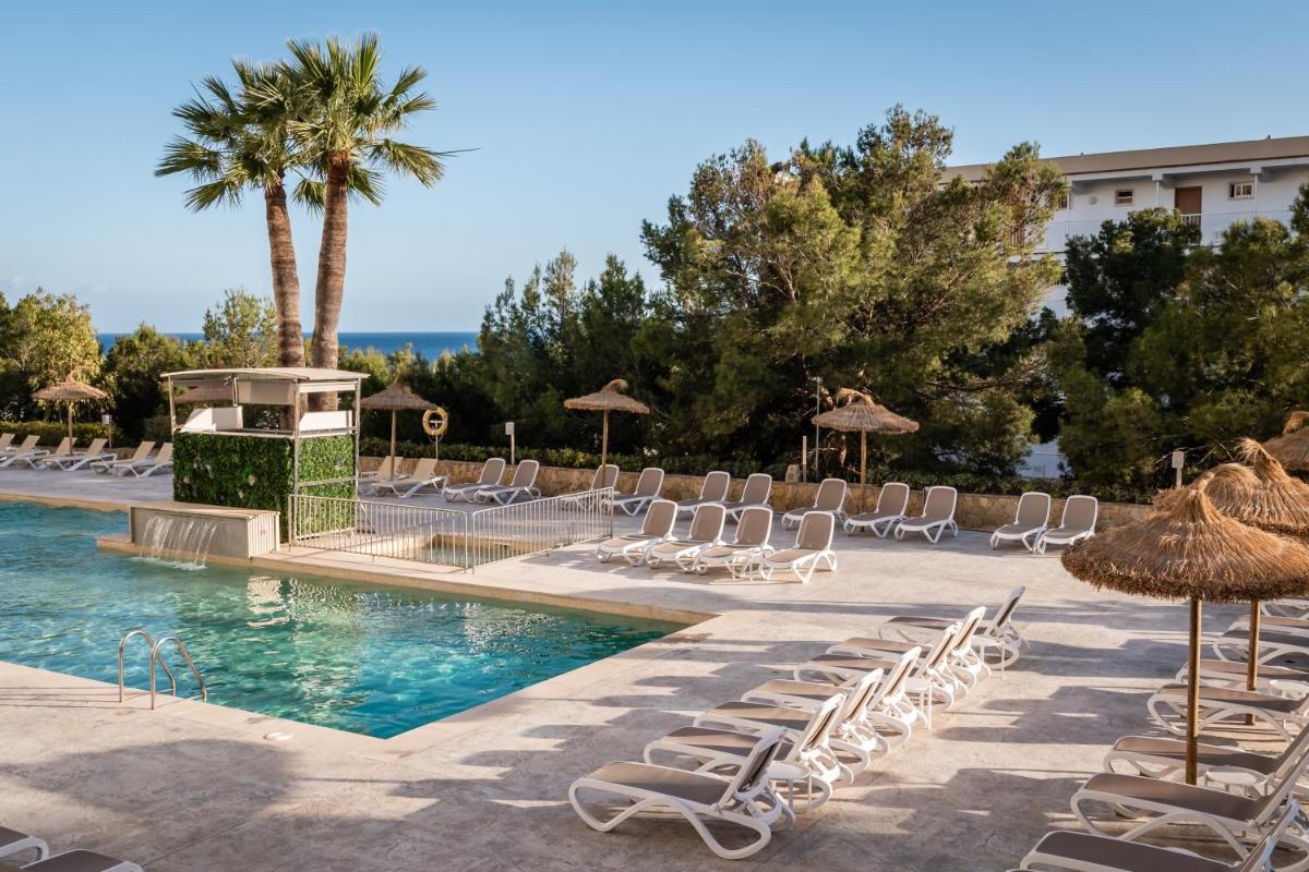 una piscina con tumbonas y sombrillas en Apartamentos Vistasol, en Magaluf