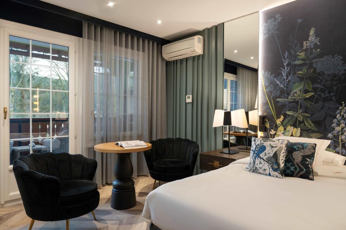 une chambre d'hôtel avec un lit, une table et des chaises dans l'établissement LA CHENEAUDIÈRE - Hôtel Spa - Relais & Châteaux - Restaurant étoilé, à Colroy-la-Roche