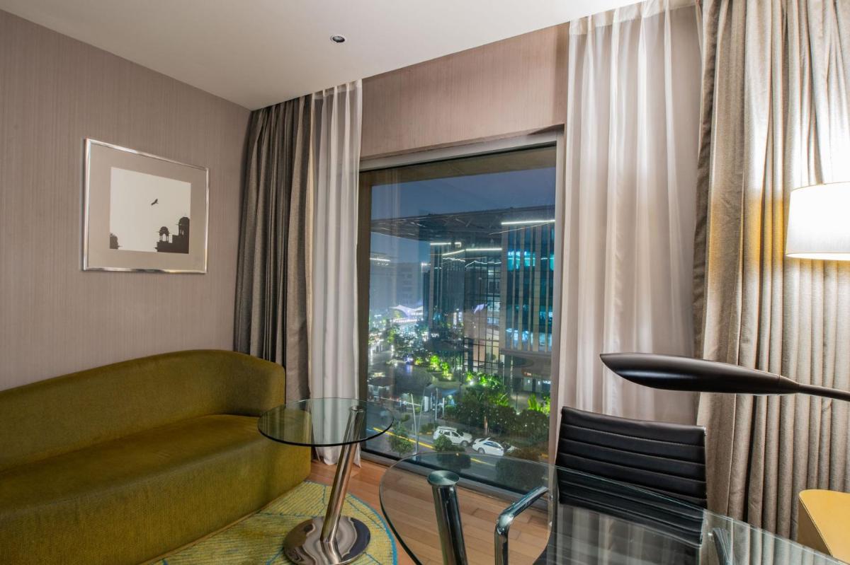 a living room with a glass table in front of a window at Holiday Inn New Delhi Aerocity by IHG in New Delhi