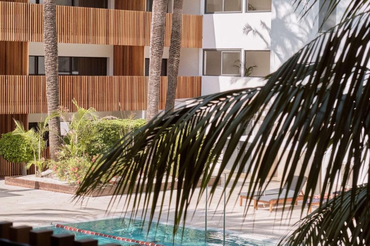 una palmera delante de un edificio en Las Gaviotas Suites Hotel & Spa, en Playa de Muro