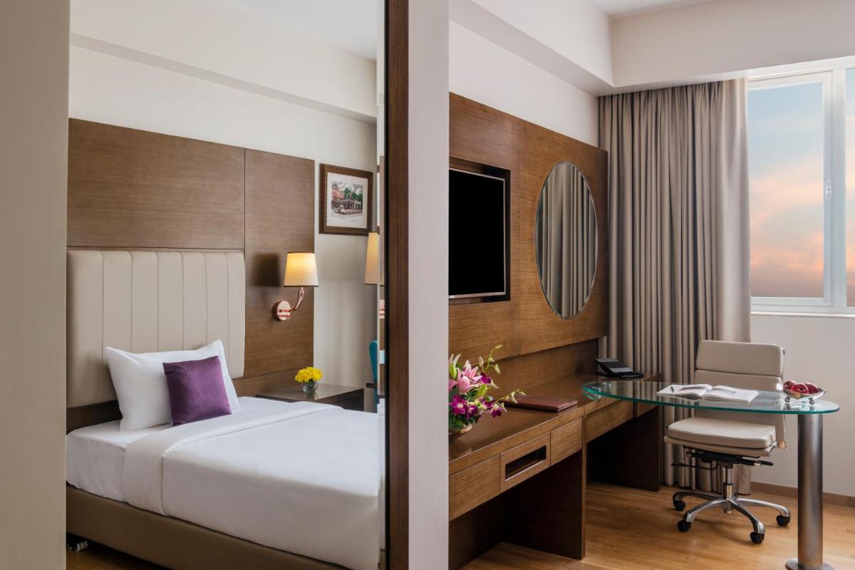 a hotel room with a bed and a desk at Vivanta Thiruvananthapuram in Trivandrum