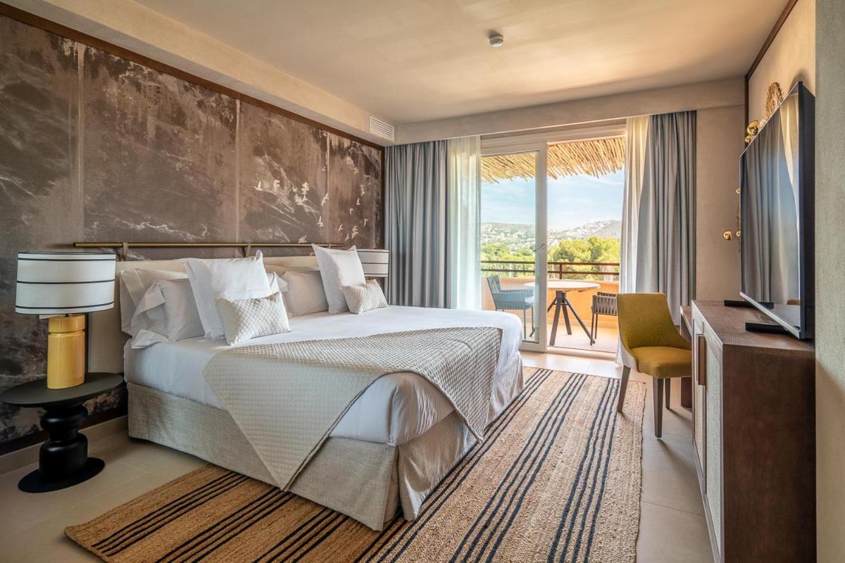 Un dormitorio con una cama grande y un balcón. en Hotel Ritual de Terra & SPA Moraira, en Moraira