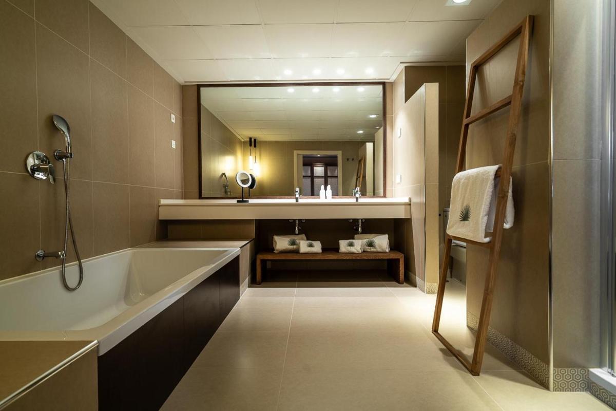 Un baño con bañera y un espejo grande. en Hotel Ritual de Terra & SPA Moraira, en Moraira