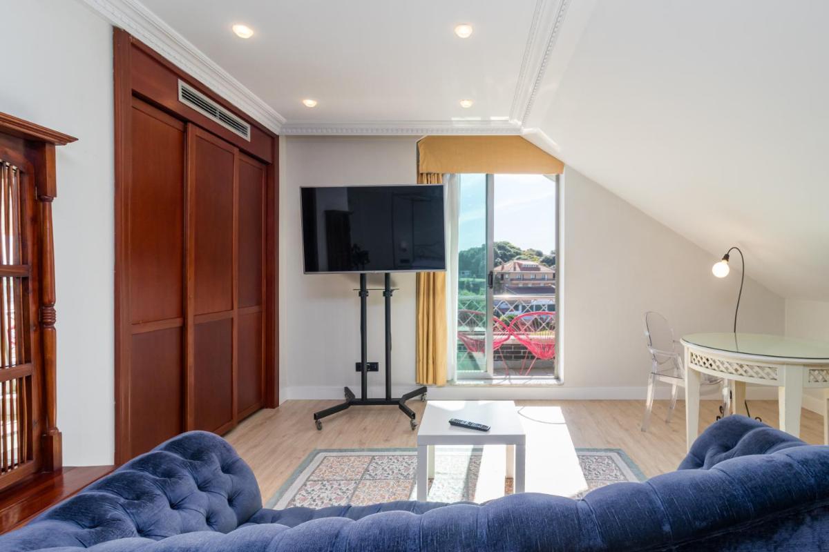 Una sala de estar con un sofá azul y una mesa. en Hotel Milagros Golf, en Mogro