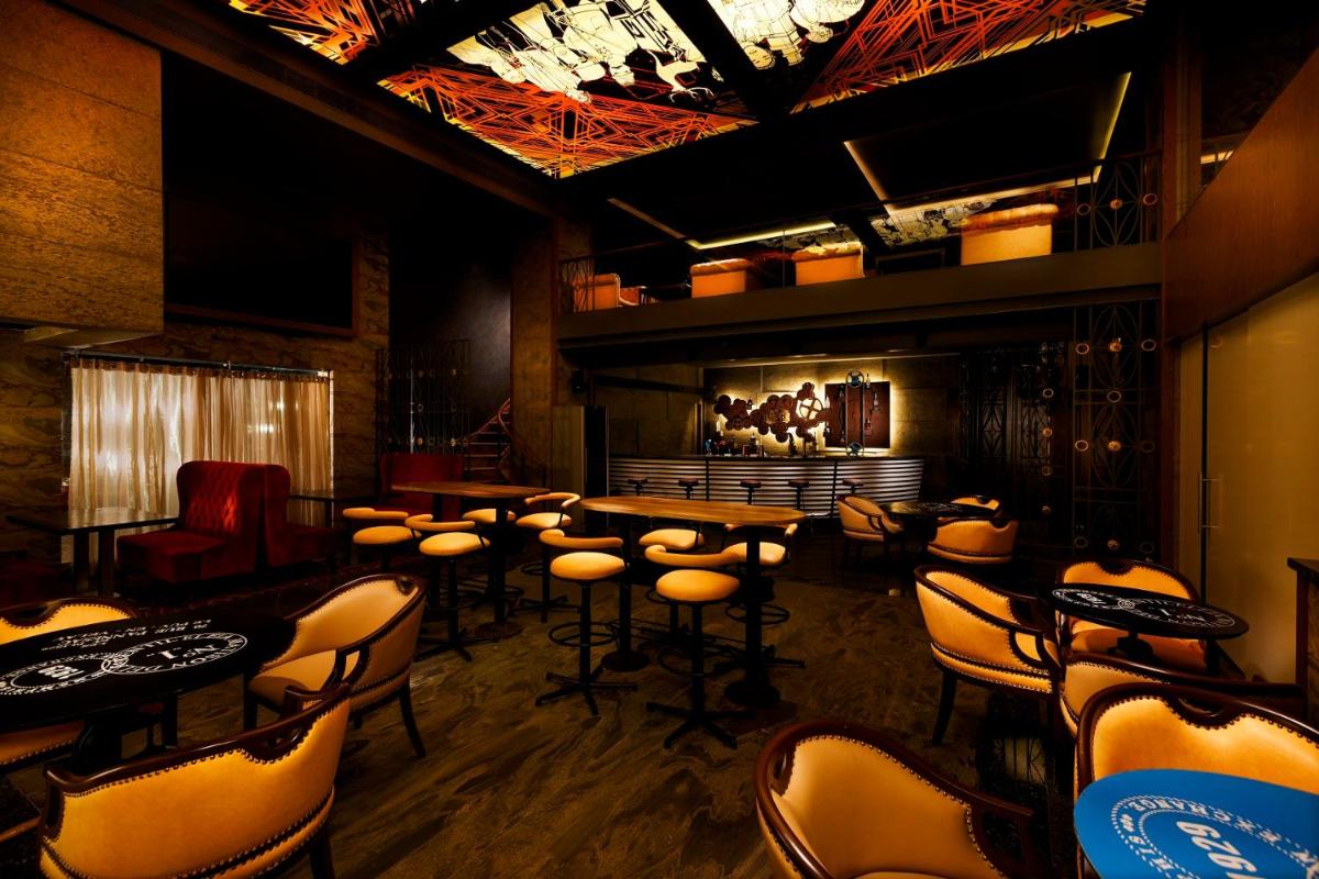 a bar with stools and tables in a room at Grand Chennai by GRT Hotels in Chennai