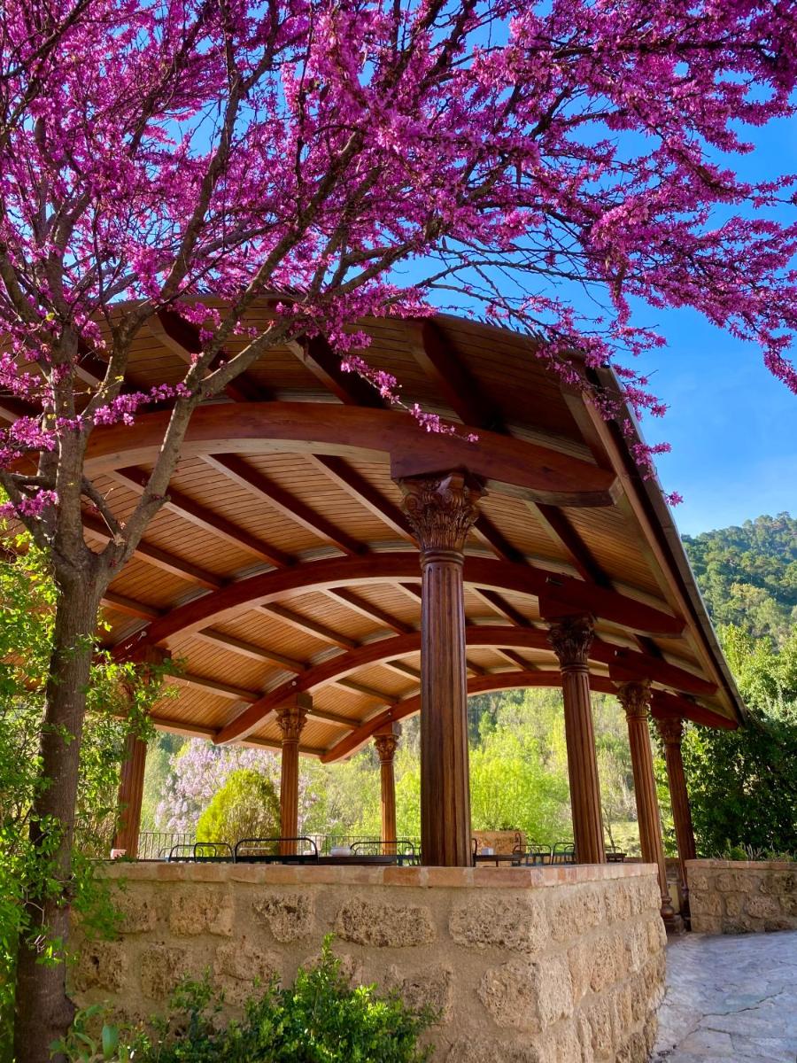 Un cenador de madera con un árbol con flores rosas. en Coto del Valle de Cazorla, en Cazorla