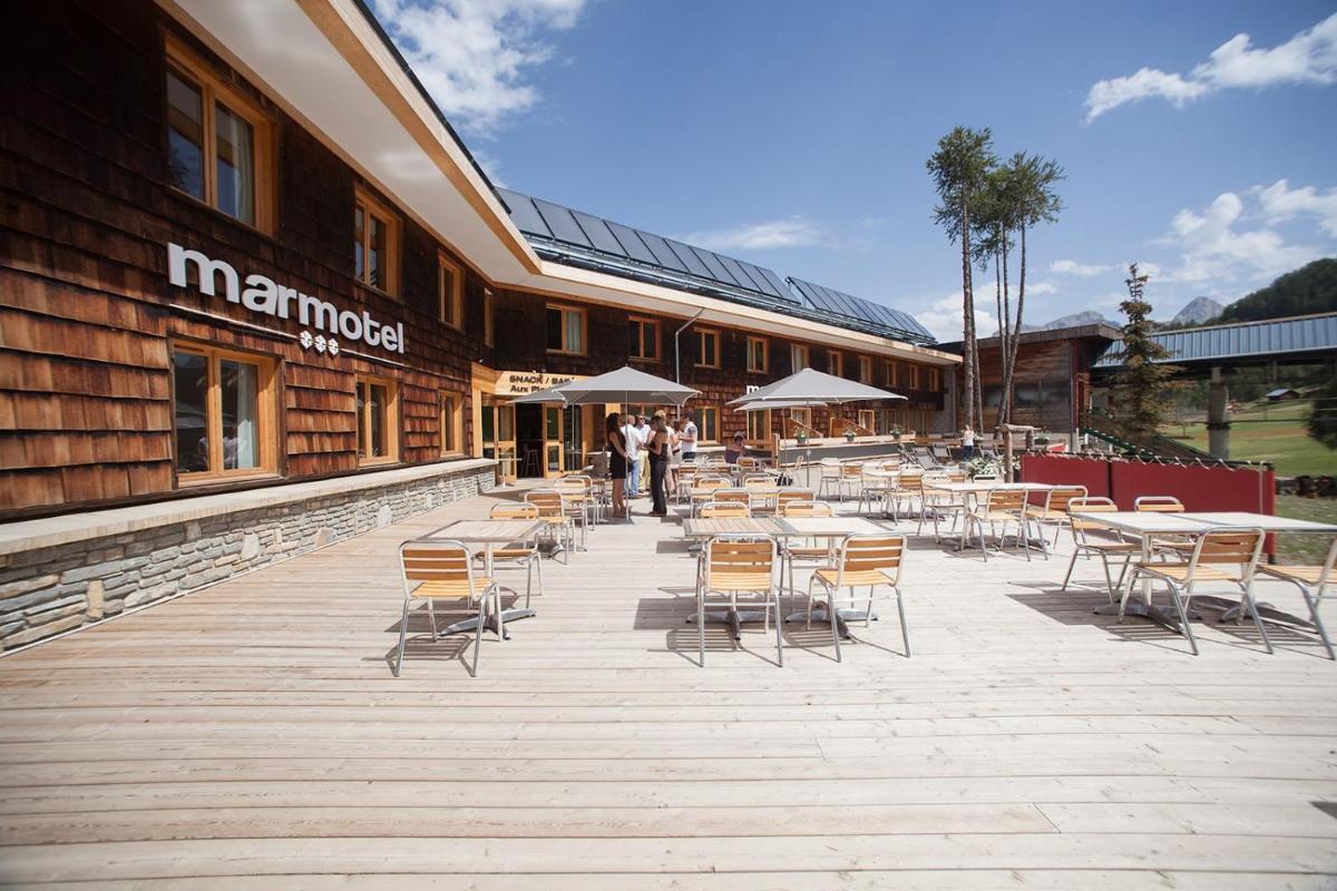 une terrasse avec des tables et des chaises devant un bâtiment dans l'établissement Marmotel & Spa, à Pra-Loup