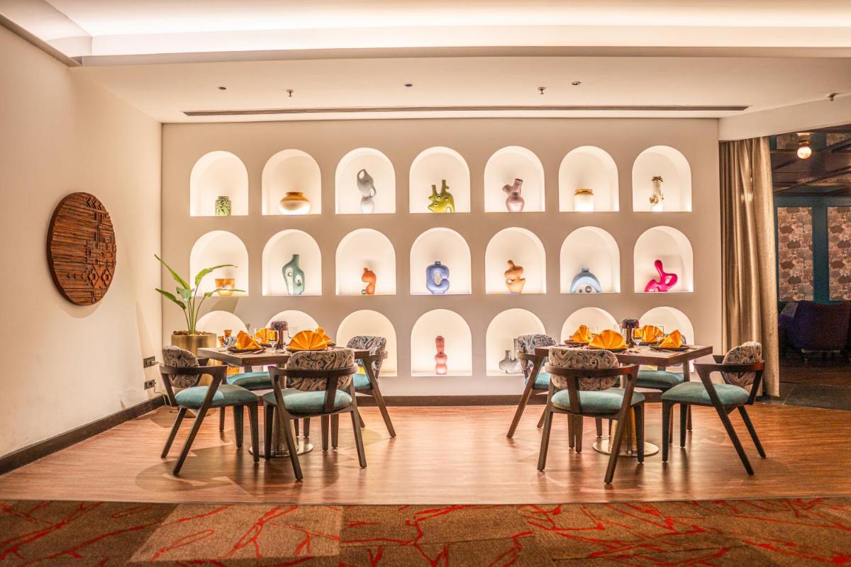 a dining room with tables and chairs and shelves of shoes at Novotel Kolkata Hotel and Residences in Kolkata a dining room with tables and chairs and shelves of shoes at Novotel Kolkata Hotel and Residences in Kolkata
