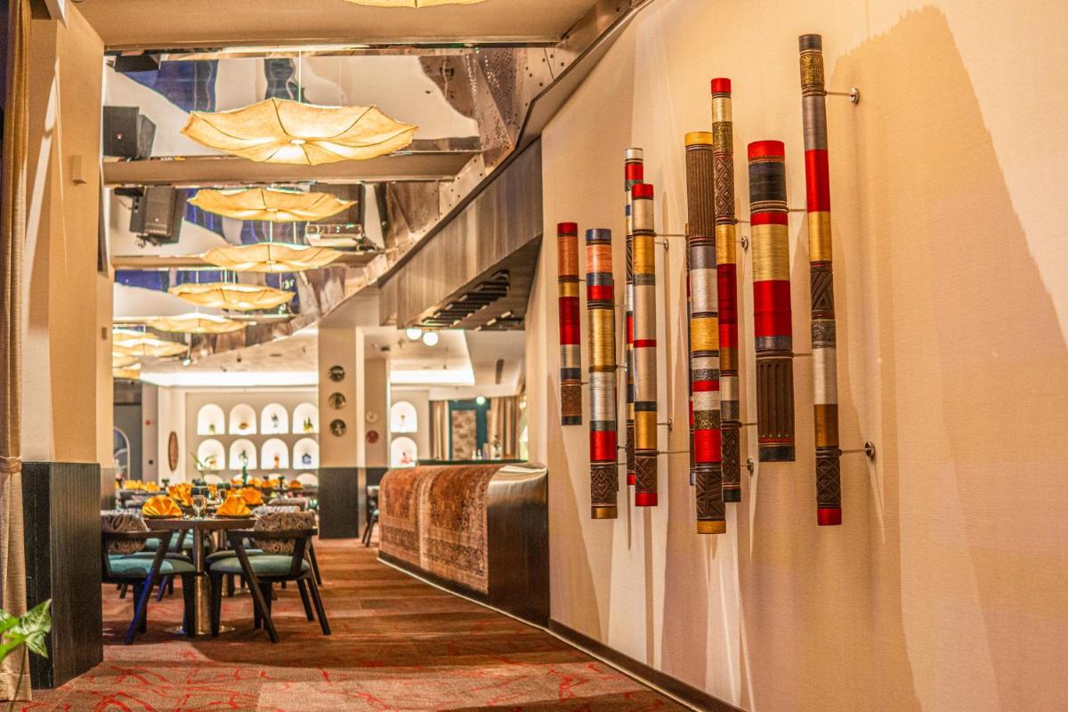 a restaurant with a row of wine bottles on the wall at Novotel Kolkata Hotel and Residences in Kolkata a restaurant with a row of wine bottles on the wall at Novotel Kolkata Hotel and Residences in Kolkata