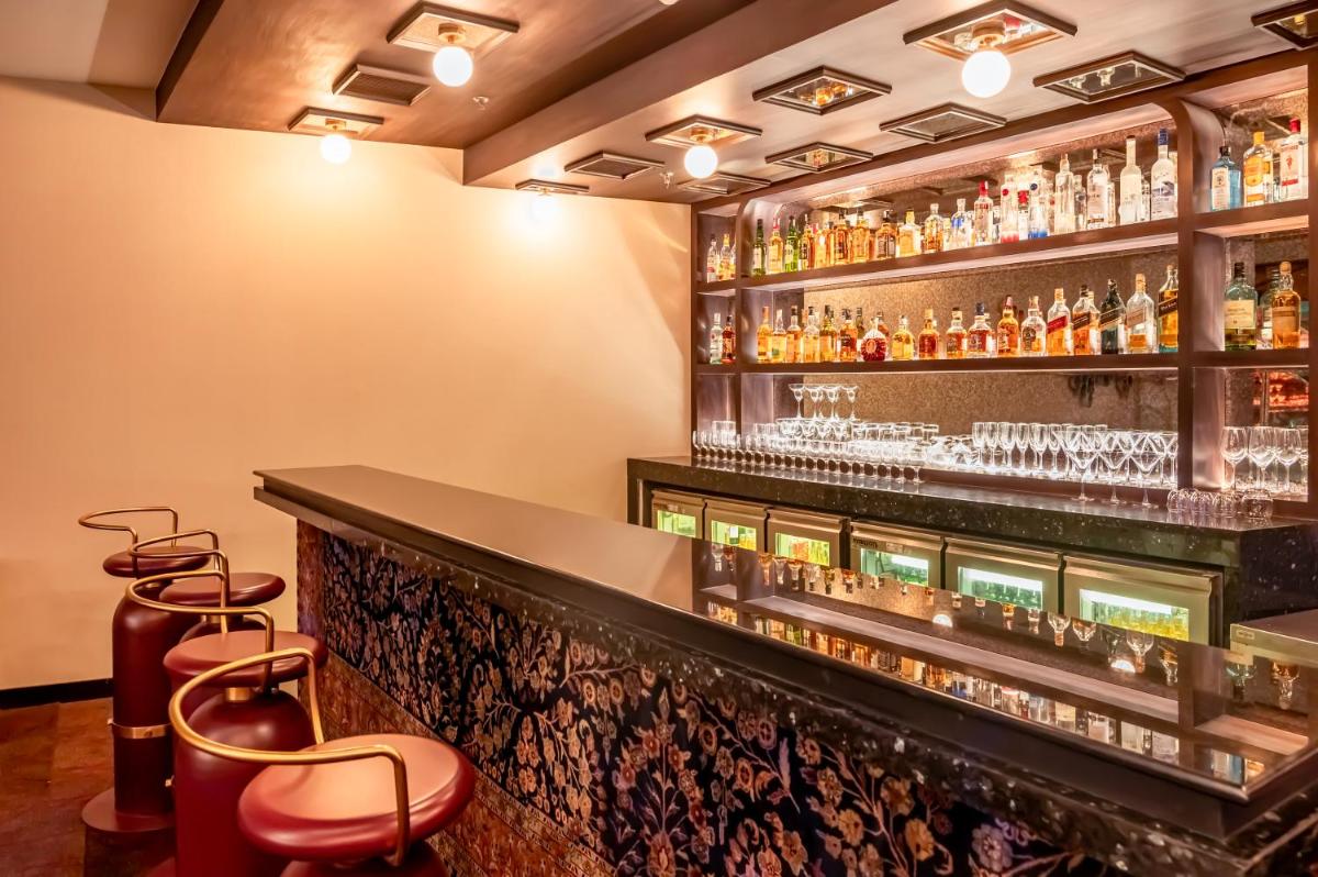a bar with bar stools and alcohol bottles at Novotel Kolkata Hotel and Residences in Kolkata a bar with bar stools and alcohol bottles at Novotel Kolkata Hotel and Residences in Kolkata