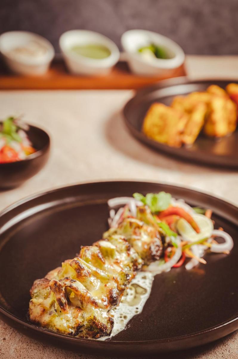 a piece of pizza on a black plate with salad at Novotel Kolkata Hotel and Residences in Kolkata a piece of pizza on a black plate with salad at Novotel Kolkata Hotel and Residences in Kolkata