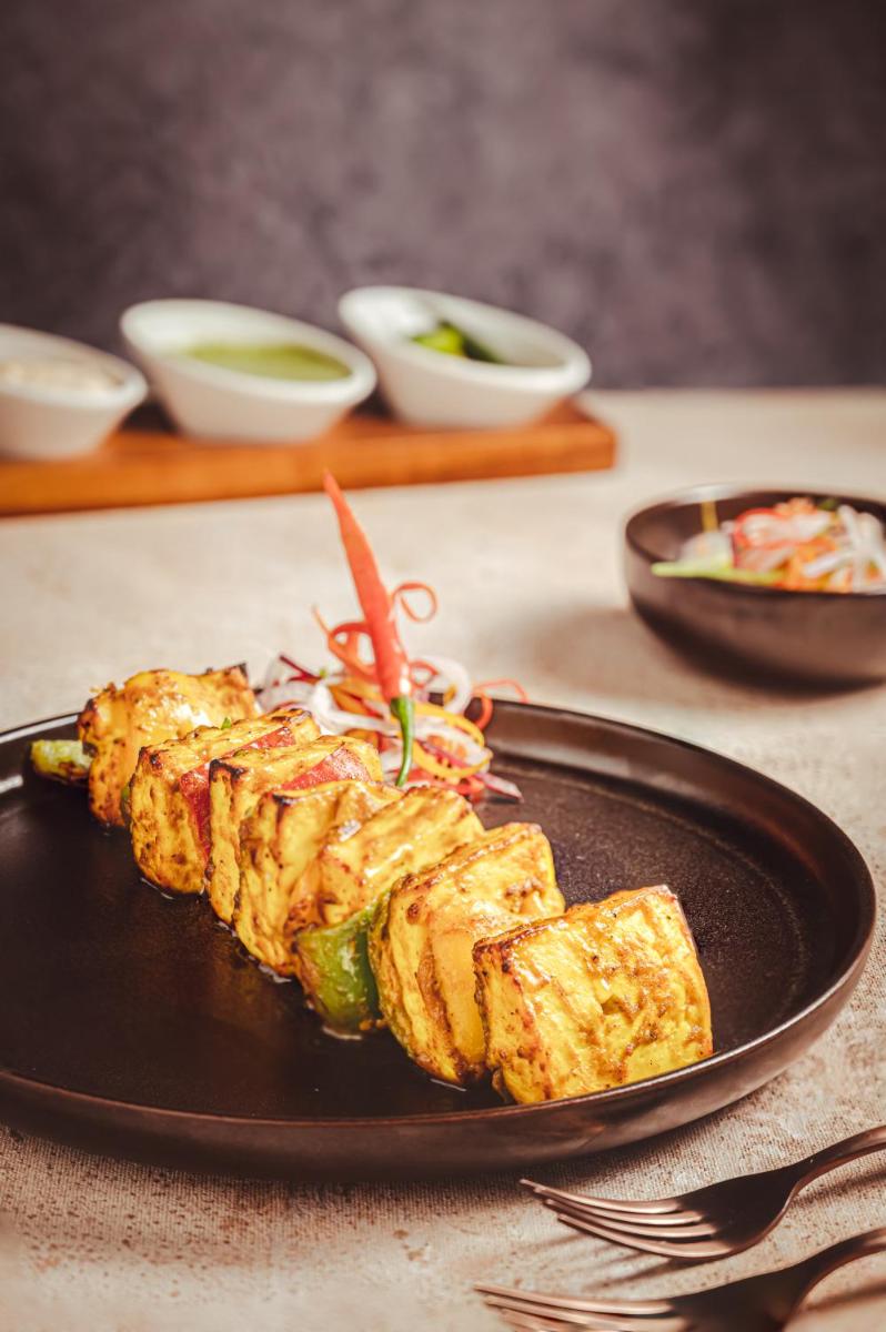 a black plate with food on a table at Novotel Kolkata Hotel and Residences in Kolkata a black plate with food on a table at Novotel Kolkata Hotel and Residences in Kolkata