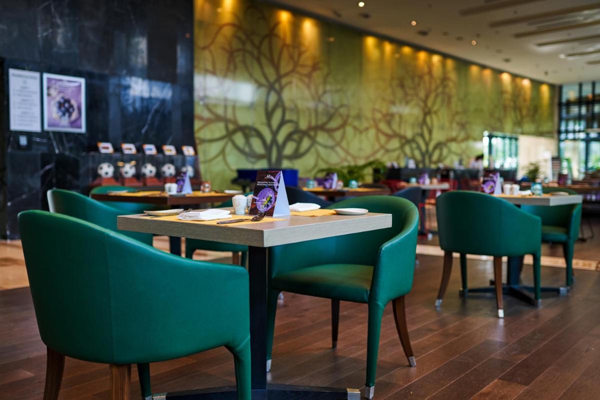 a dining room with a table and green chairs at Novotel Kolkata Hotel and Residences in Kolkata a dining room with a table and green chairs at Novotel Kolkata Hotel and Residences in Kolkata