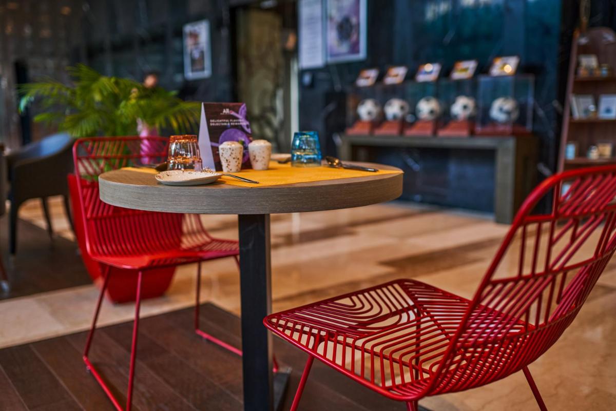 a table and two red chairs in front of a store at Novotel Kolkata Hotel and Residences in Kolkata a table and two red chairs in front of a store at Novotel Kolkata Hotel and Residences in Kolkata