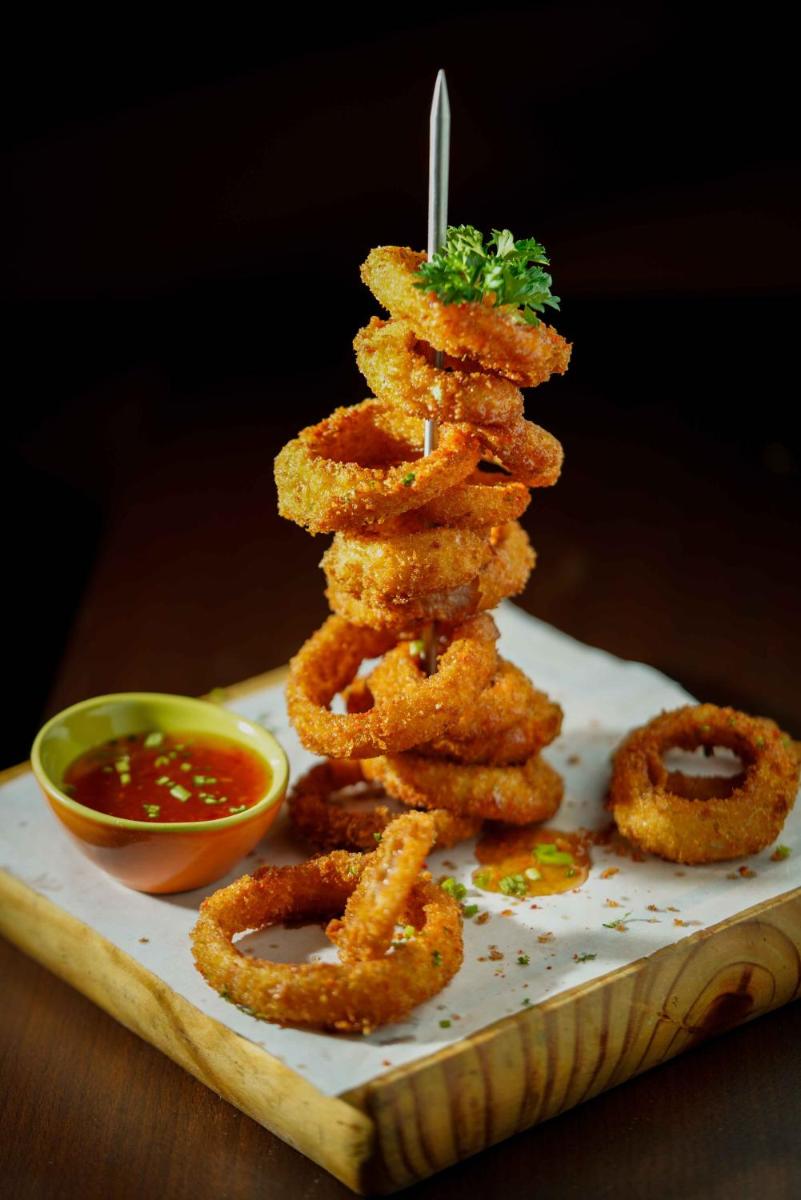a pile of onion rings and dipping sauce on a plate at Novotel Kolkata Hotel and Residences in Kolkata a pile of onion rings and dipping sauce on a plate at Novotel Kolkata Hotel and Residences in Kolkata