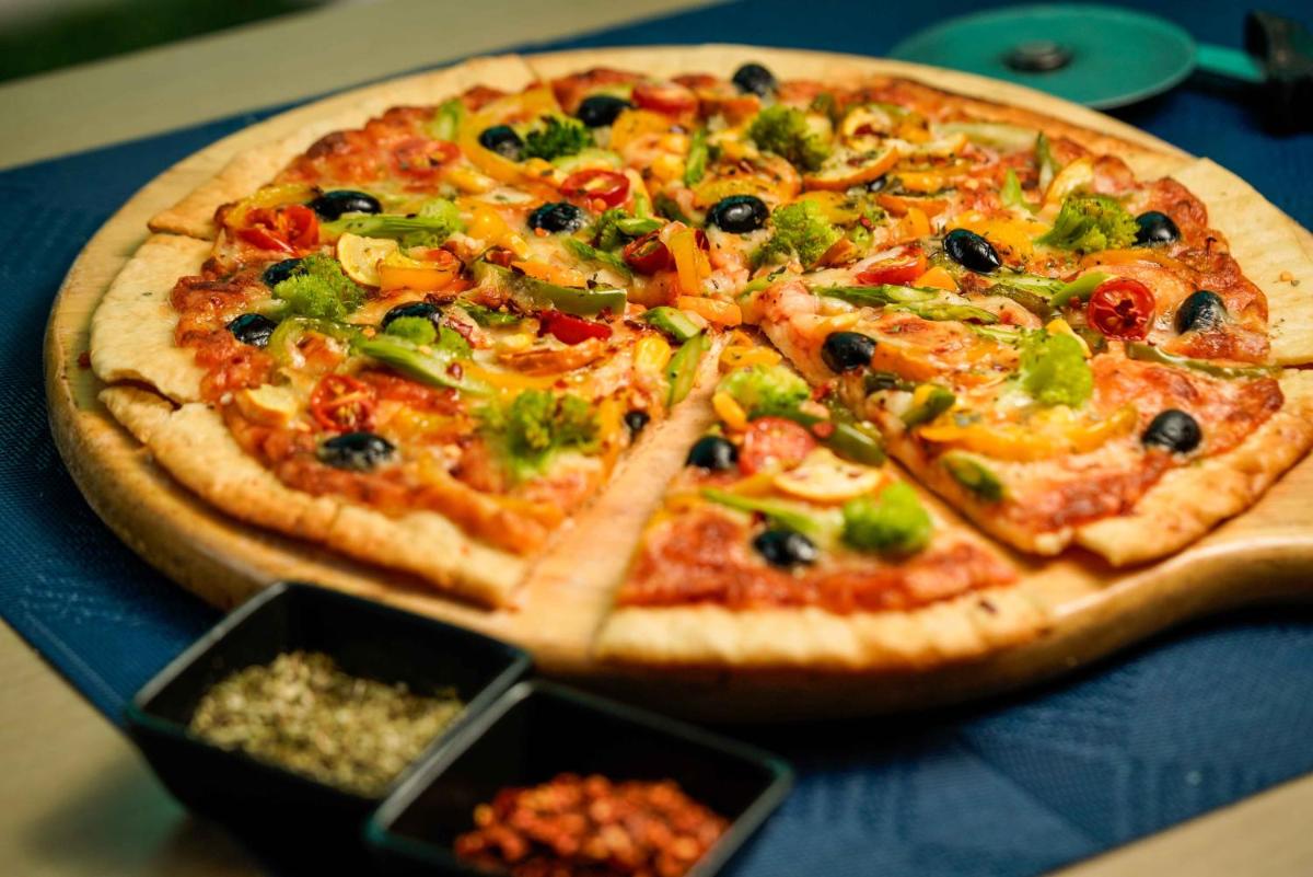 a pizza sitting on top of a table at Novotel Kolkata Hotel and Residences in Kolkata a pizza sitting on top of a table at Novotel Kolkata Hotel and Residences in Kolkata