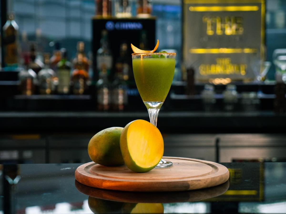 a drink with an orange and some fruit on a table at Novotel Kolkata Hotel and Residences in Kolkata a drink with an orange and some fruit on a table at Novotel Kolkata Hotel and Residences in Kolkata