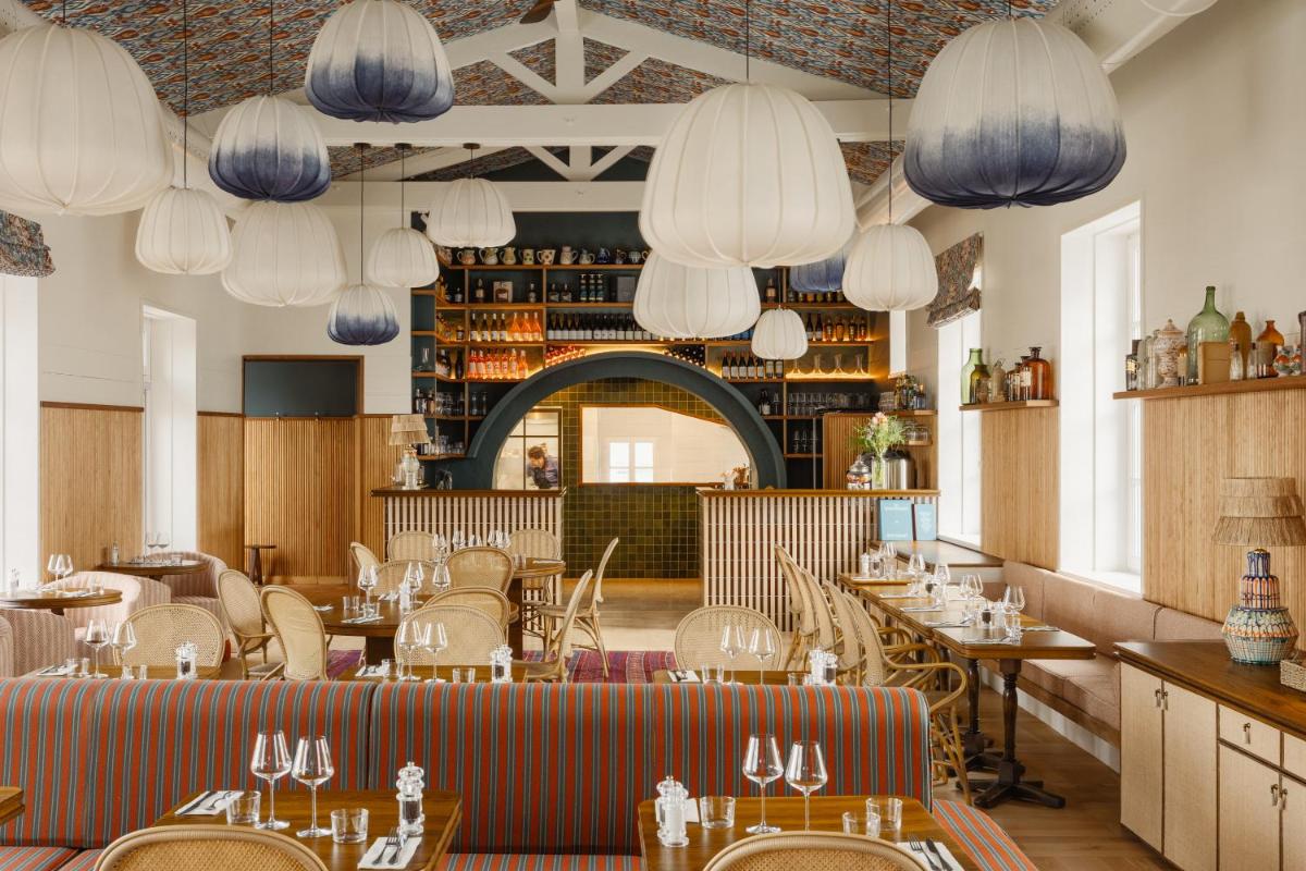 un restaurant avec des tables, des chaises et des lumières dans l'établissement La Mission Hôtel & SPA - l'île d'Yeu, à L'Ile d'Yeu