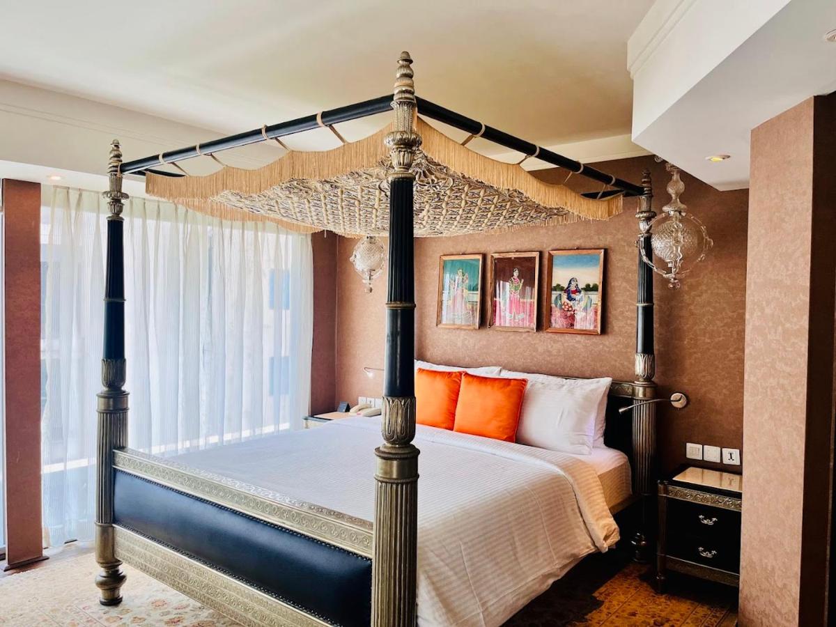a bedroom with a four poster bed with orange pillows at The Park Hyderabad, Banjara Hills near Hussain Sagar Lake in Hyderabad a bedroom with a four poster bed with orange pillows at The Park Hyderabad, Banjara Hills near Hussain Sagar Lake in Hyderabad