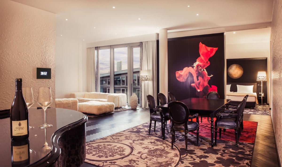 ein Wohnzimmer mit Tisch und Stühlen und einer Couch in der Unterkunft Kameha Grand Bonn in Bonn ein Wohnzimmer mit Tisch und Stühlen und einer Couch in der Unterkunft Kameha Grand Bonn in Bonn