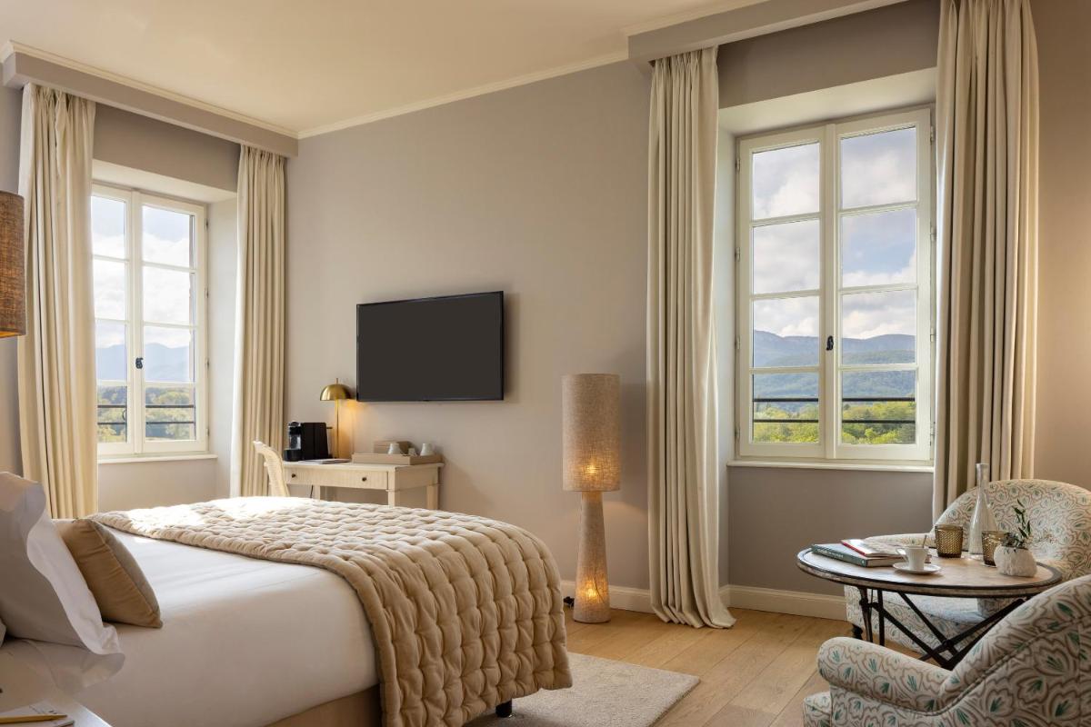 une chambre avec un lit, une télévision et des fenêtres dans l'établissement Château Les Oliviers de Salettes, à Charols