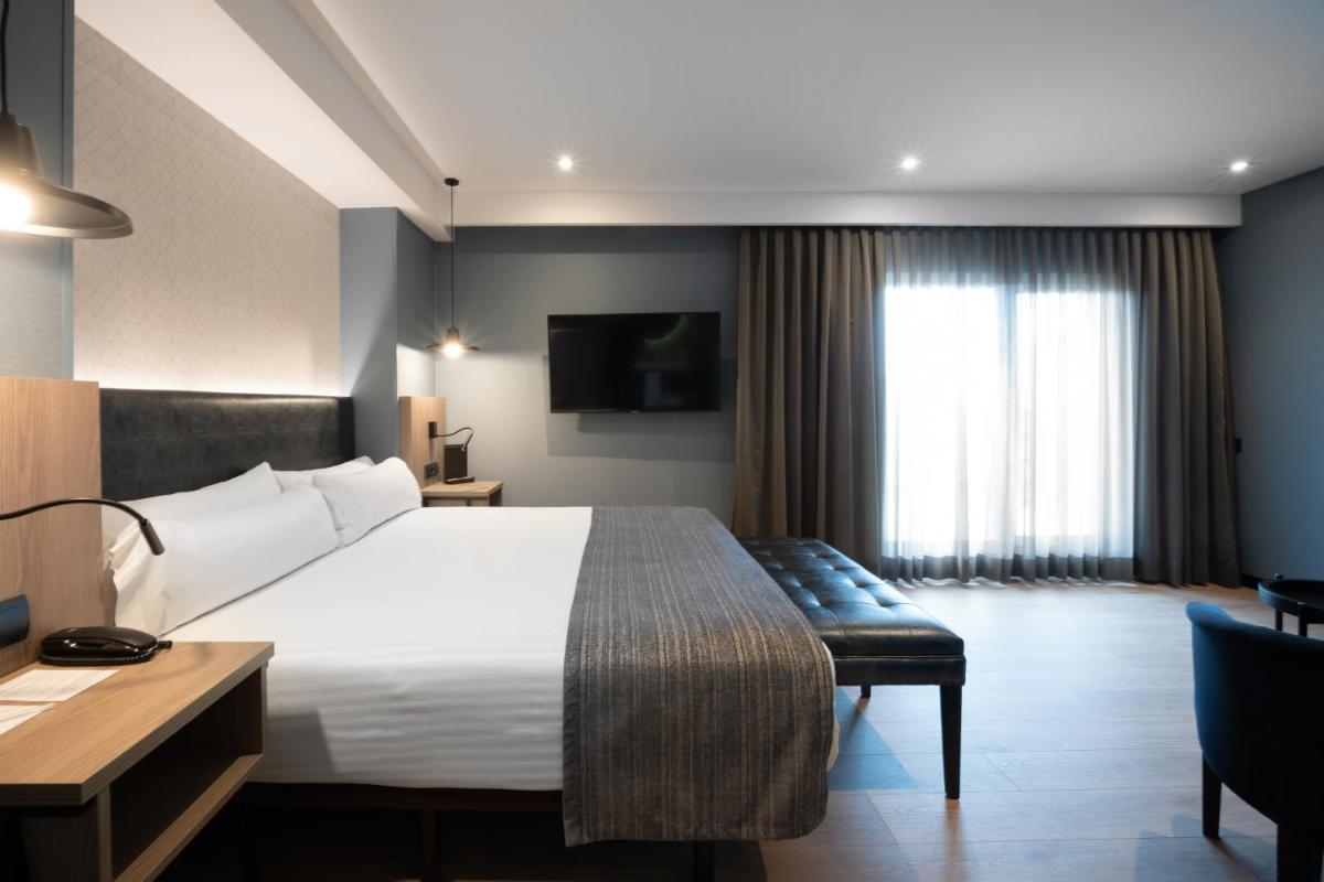 Una habitación de hotel con una cama, un escritorio y un televisor. en Catalonia Atenas, en Barcelona