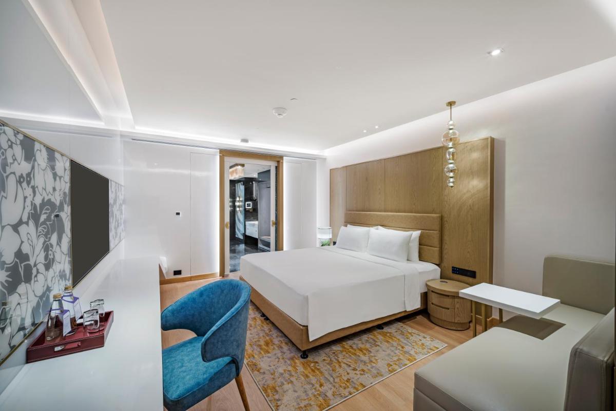 a bedroom with a white bed and a blue chair at Radisson Blu Hotel & Suites GRT Chennai in Chennai