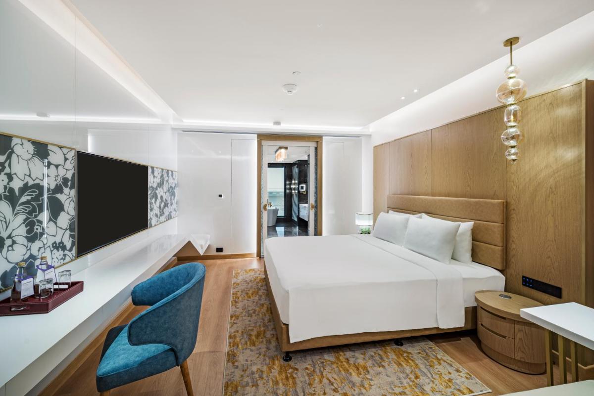 a bedroom with a white bed and a blue chair at Radisson Blu Hotel & Suites GRT Chennai in Chennai