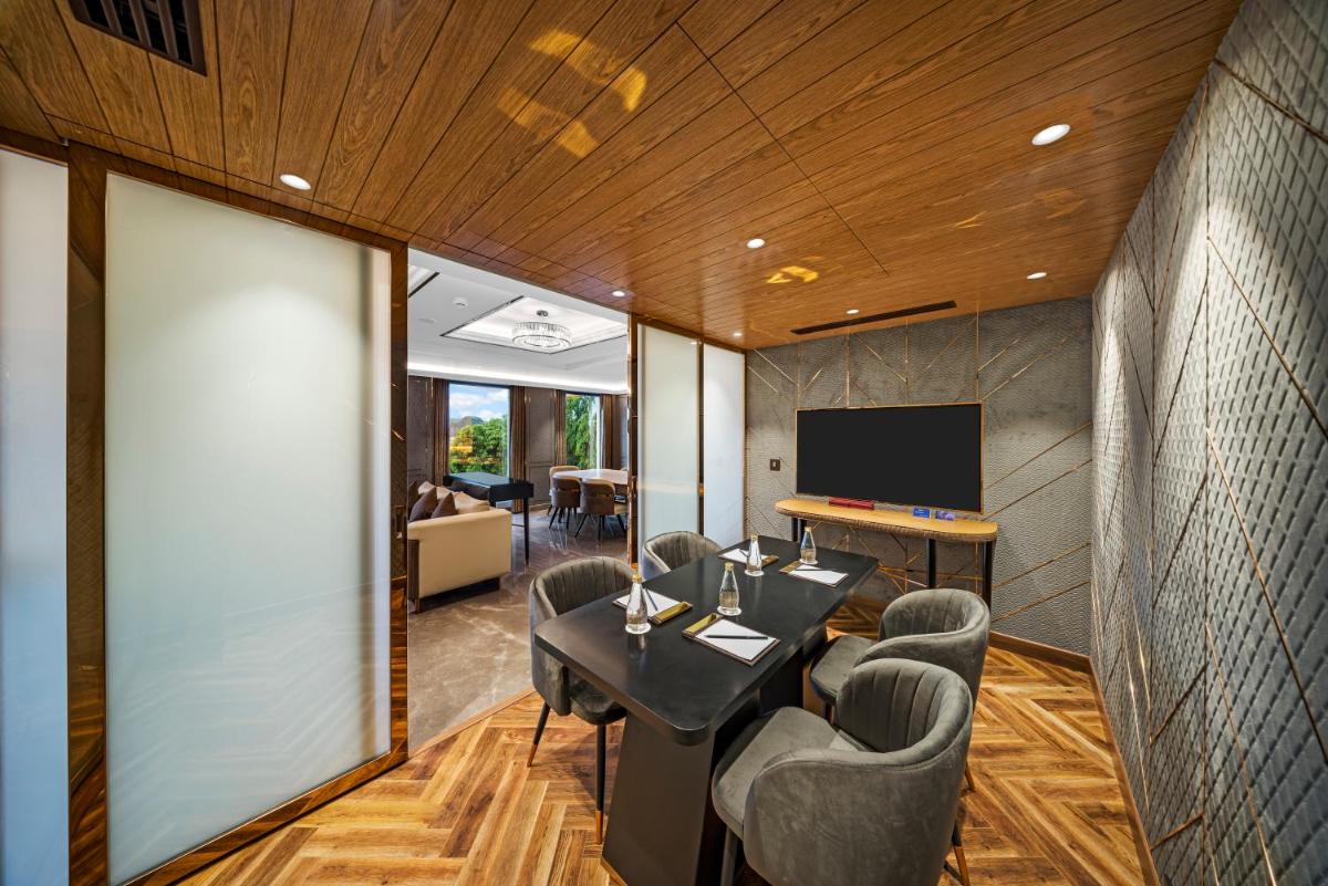 a room with a table and chairs and a tv at Radisson Blu Hotel & Suites GRT Chennai in Chennai