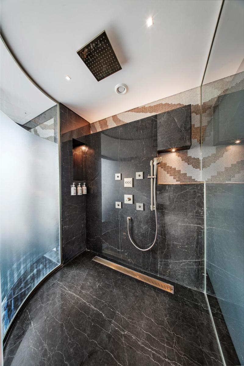 a bathroom with a shower with black tiles at Radisson Blu Hotel & Suites GRT Chennai in Chennai