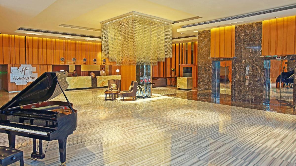 a hotel lobby with a piano and a chandelier at Holiday Inn New Delhi Mayur Vihar Noida by IHG in New Delhi a hotel lobby with a piano and a chandelier at Holiday Inn New Delhi Mayur Vihar Noida by IHG in New Delhi