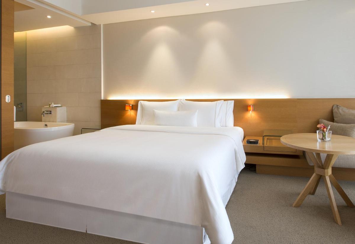 a bedroom with a large white bed and a bathroom at The Westin Mumbai Garden City in Mumbai