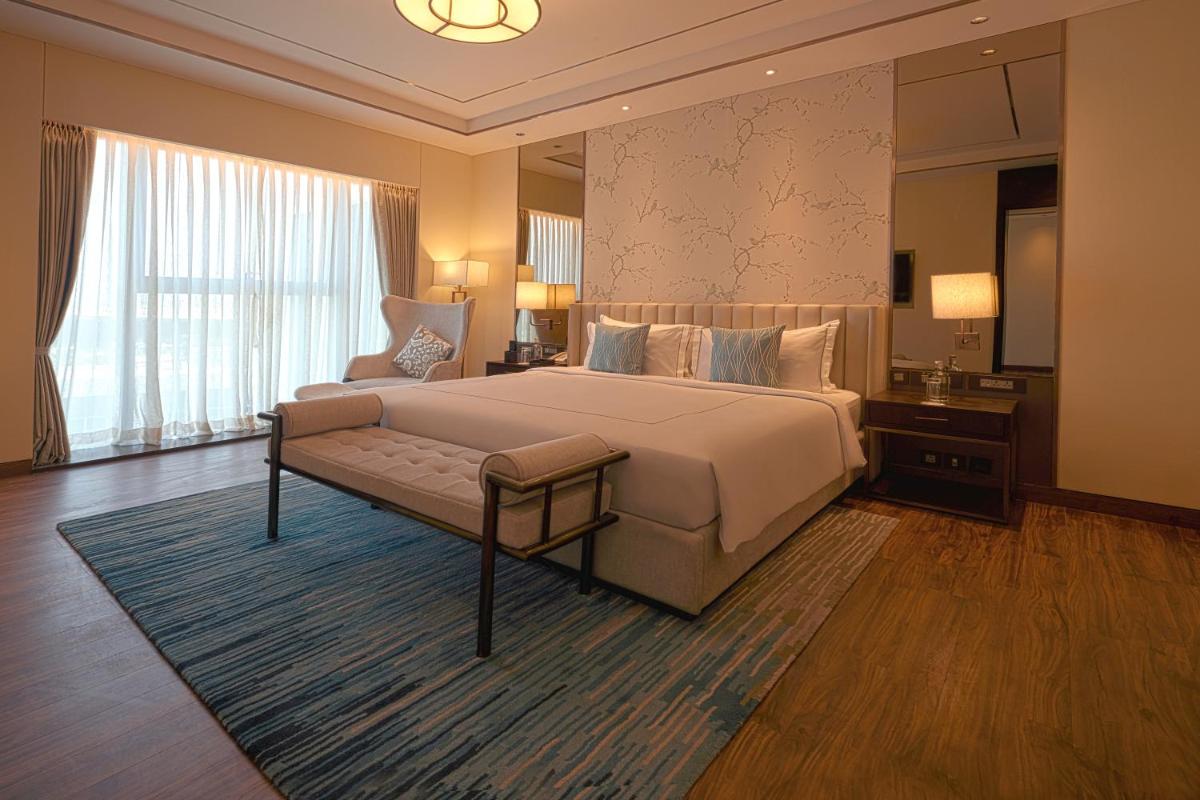 a bedroom with a large bed and a large window at Taj Bangalore in Devanahalli-Bangalore