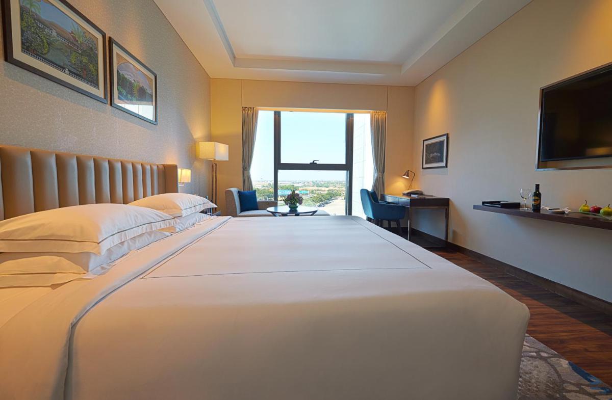 a hotel room with a large white bed with a window at Taj Bangalore in Devanahalli-Bangalore