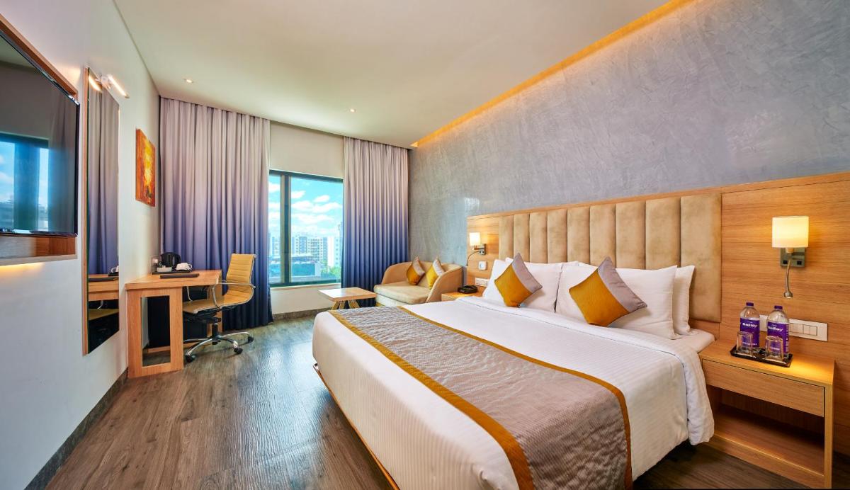 a hotel room with a large bed and a desk at Sayaji Pune in Pune