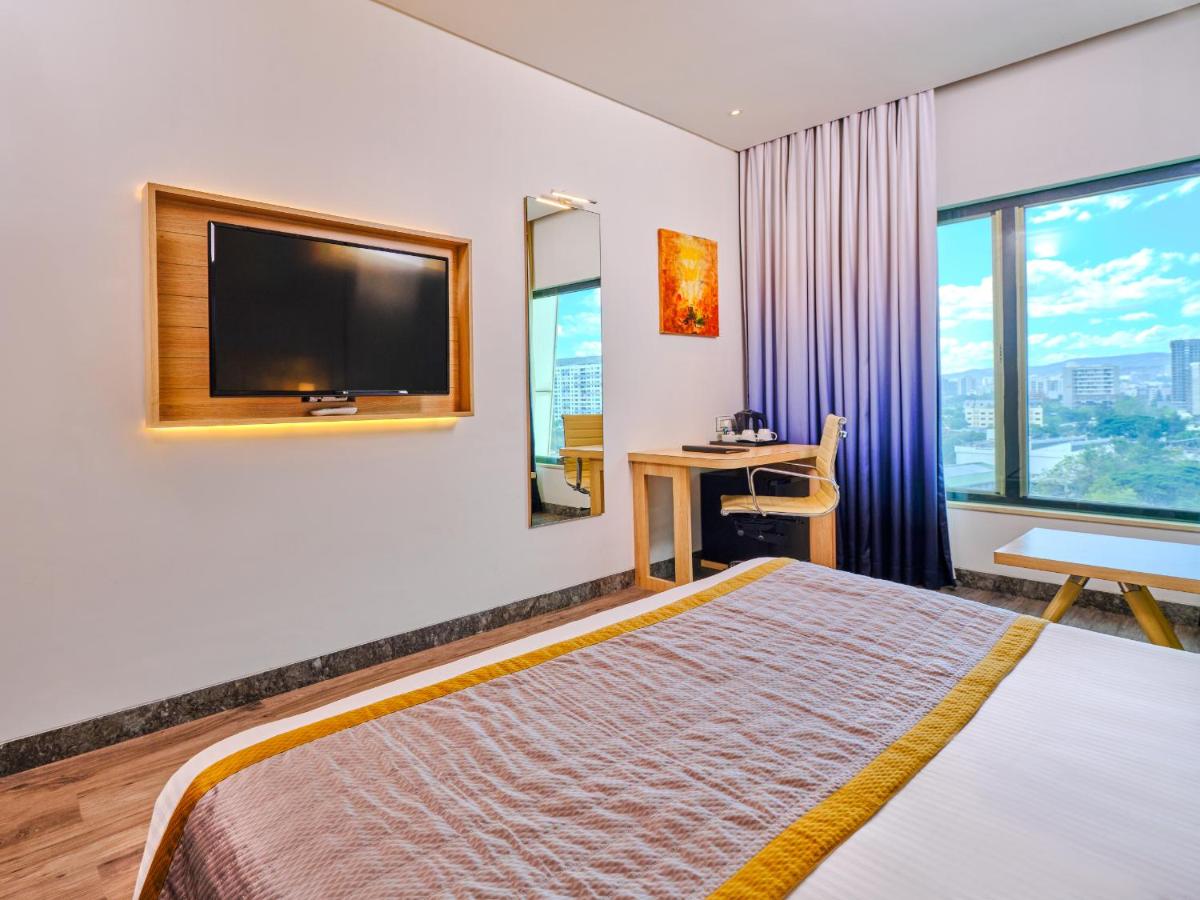 a hotel room with a bed and a flat screen tv at Sayaji Pune in Pune