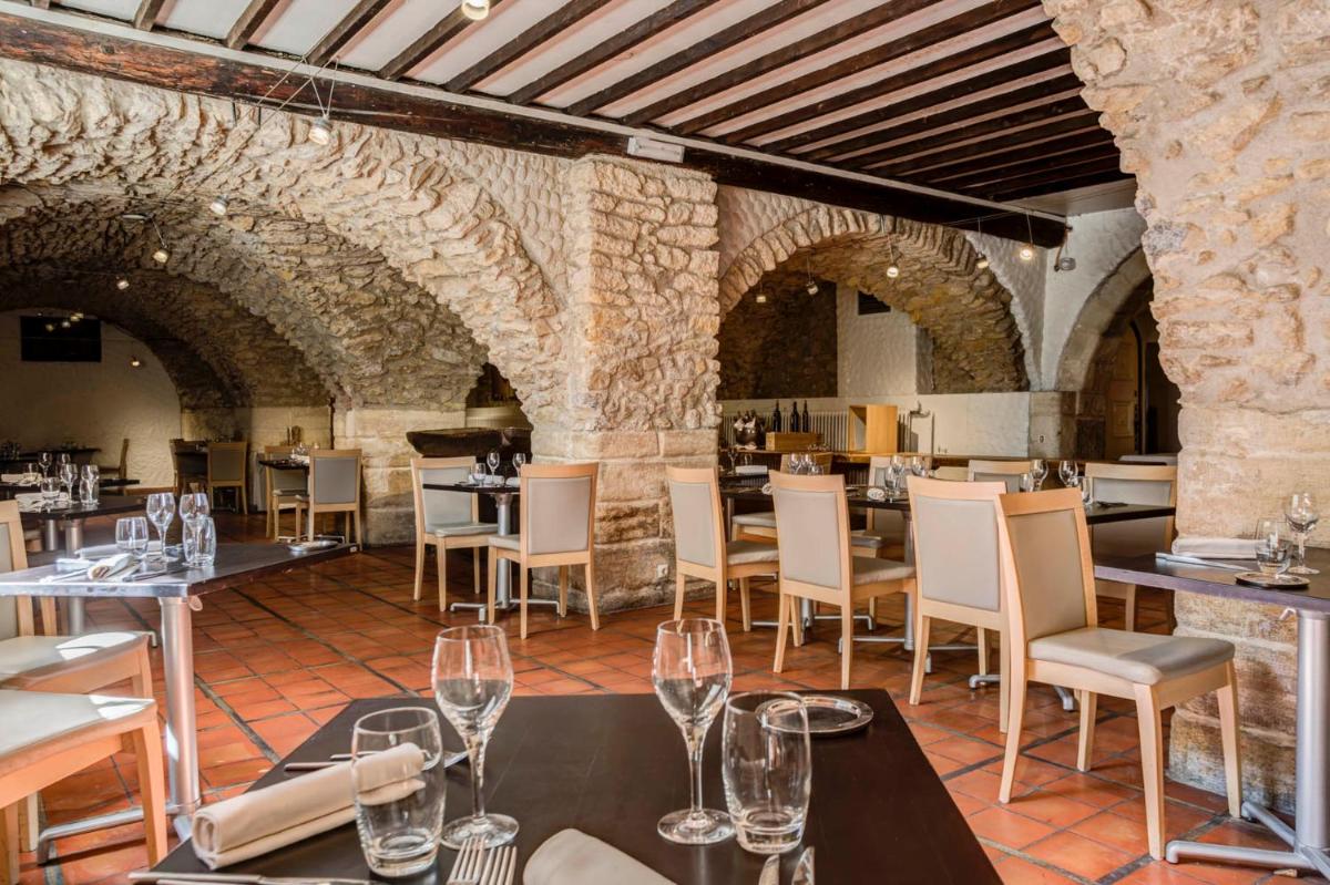 - un restaurant avec des tables et des chaises dans une salle aux murs en pierre dans l'établissement Hôtel du Golf, à Mallemort