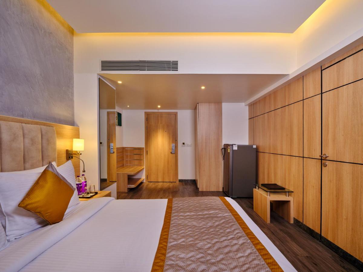a hotel room with a bed and a refrigerator at Sayaji Pune in Pune