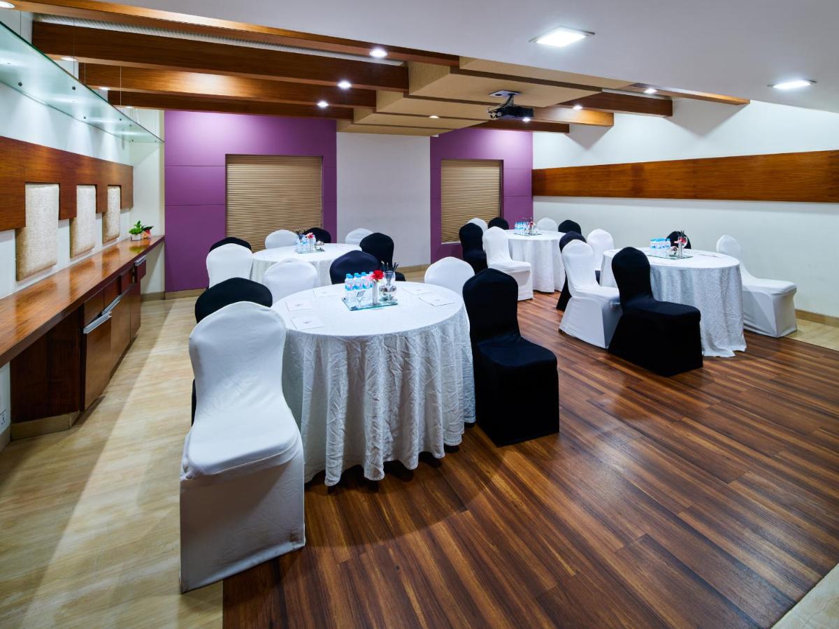 a banquet hall with white tables and black chairs at Sayaji Pune in Pune