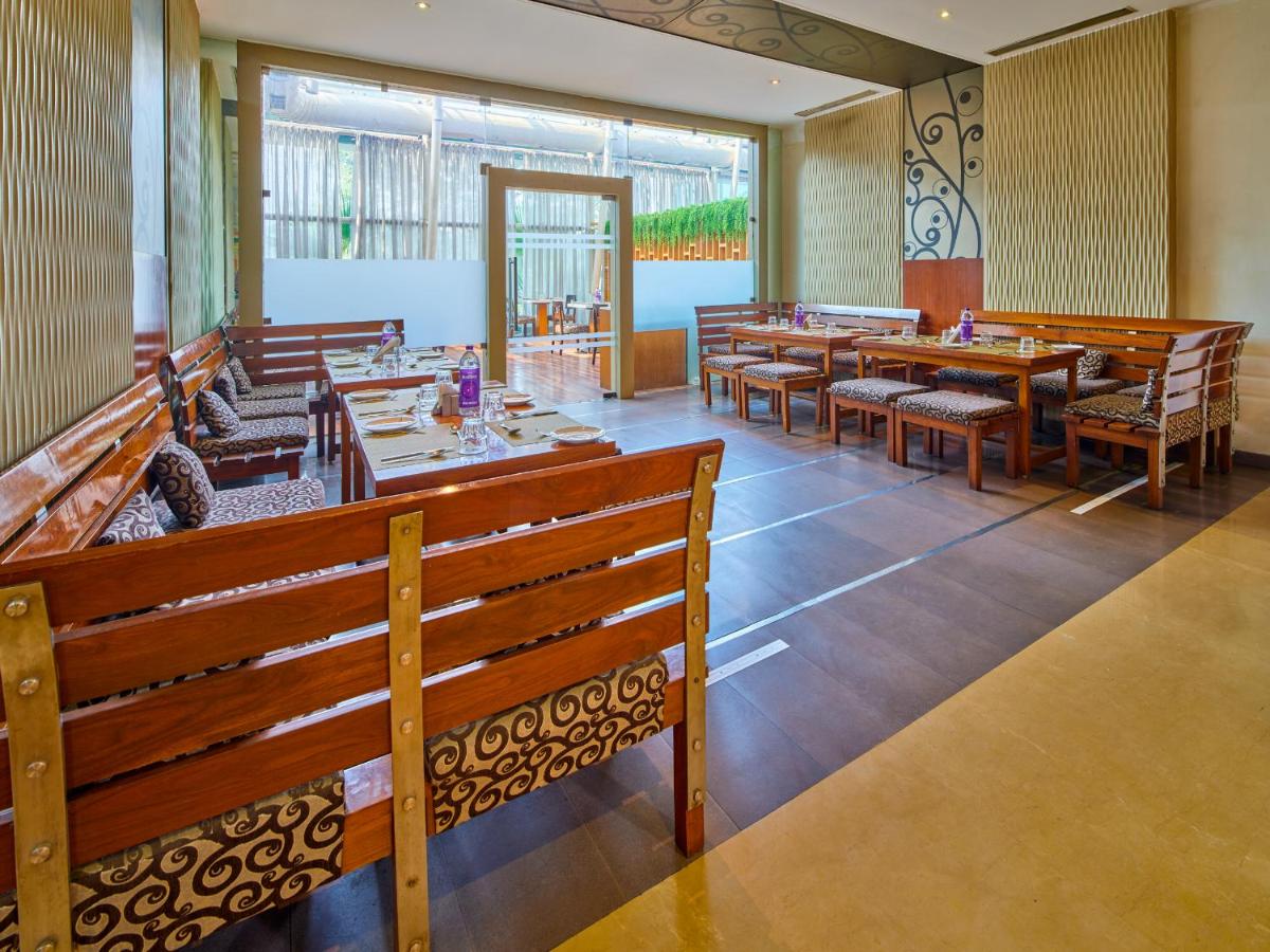 a dining room with wooden tables and chairs at Sayaji Pune in Pune